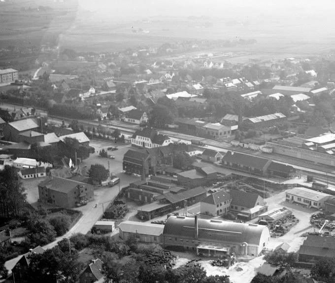  Luftfotos er altid sjove. Så kommer alt lidt i fugleperspetiv. Der er mange ting her på billedet, der var i 1950erne. Midt i billedet er der Tagpap fabrikken Phønix. Der er jernbanen med banegården, og den gamle rutebilstation, og Vejen sydpå. Ja Alfas høje skorsten kunne ses fra mange sider i Vejen. Og ikke mindst vejen op til højbro lige foran, Skovvejen.
Det var den gang at Vejen by var en homogen  enhed,  rent bygningsmæssigt.
 