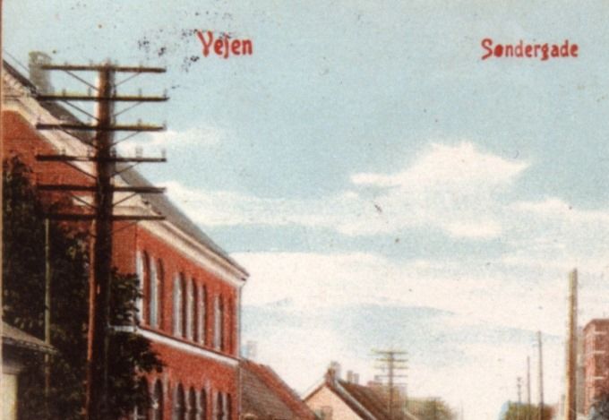 Søndergade Vejen, set mod syd.
Et rigtigt dejlig postkort fra Søndergade.
Jeg må indrømme at det har taget lidt tid at finde ud af hvor det er.
Til venstre er det Posthuset, og til højre er det Jyllandsgade der går til højre i billedet. Og det må så være Peder Lauridsens Kolonialforretning i Søndergade 10.
Peder Lauridsen var halvbroder til Johannes Lauridsen på Grønvang, og som byggede Brejdablik på Askovvej, til ham og hans kone.
I samme bygning var der til venstre for Købmandsbutikken Manufakturhandler H. C. Lund med Oplag for Chrome & Goldscmidt. 1909.
Og i min tid 
Juel Pedersen,   Konfektion, Kjoler og Sengeudstyr. 1954.
Til venstre igen ligger med den lyse gavl   Slagterforretningen ved Peder Knudsen
 1960- 1982. Der sørgeligt nok døde i en alt for ung alder.
Slagtermester Peder Knudsen, Præstevænget 18, Vejen, 55 år,  20. maj 1982.
 Overfor på højre side var der bl.a.  Tatol ved Anna Kathrine Petersen som vi derhjemme kaldte Tatolpetter. Der havde alt lige fra Sæbe til Succes chokolade med 100 andre ting.
 Det er helt dejligt at se hestevognene, hvor den ene har mælkejunger. Inden jeg begyndte min skolegang i 1953  var der tre gårde tæt på Askovvej nr. 29, hvor jeg kunne høre når mælkejungerne blev vasket til næste dags brug. Siden da jeg var i skolepraktik hos  Gaardejer Andreas Pihlkjær  har jeg også stået og spulet mælkejungerne. Der er en utrolig ro over dette billede.
Ulla Hübertz Madsen.
I Tatol har jeg købt mange legoklodser, dengang kunne man købe dem enkeltvis. Husker tydelig den store skuffe inddelt i mange rum. Der kunne man så vælge de klodser man manglede.