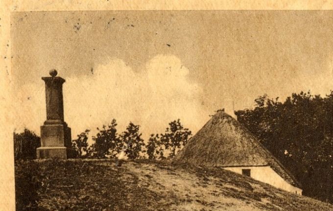  Beskrivelse. 
Postkort med parti fra Skibelund Krat.
Årstal 1922.
 Så forlader jeg Skibelund Krat  for  denne omgang.
Kæmpehøjen ved siden af det lille hvide hus har måske været større i gammel tid. 
Den er sikkert sunket lidt i de 100 år der er gået. Stakittet og stenen for neden har jeg aldrig set før, heller ikke på billeder.
Højen er helt oppe til husets tag. 
Det giver god mening at man har kaldt Restauranten  for Skibelund Pavillon, da den også ligner en Pavillon.  Og sjovt nok er den lidt  specielt bygget med de to tårne. Der har sikkert været en del ombygninger fra starten til i dag 2021.
Der står. 
En pavillon kan være et lysthus, en restaurant eller en scene i en have, park eller forlystelsesanlæg. Der kan også være tale om en tilbygning til en større bygning.
Og selvfølgelig med det danske flag, når man tænker tilbage på dens tids historie.