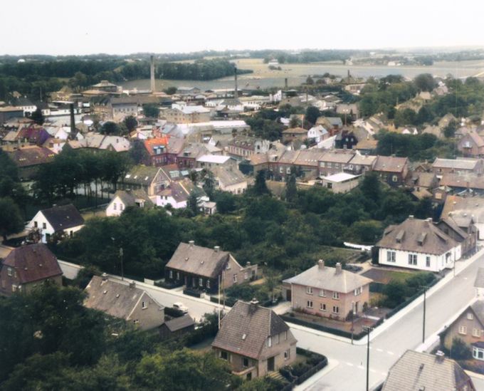    Et nyt og spændende billede her på siden.
Nederst i højre hjørne er det Museet der ligger. Med Østergade tværs i billedet, fra venstre til højre der krydser Østeralle.
Der var mange huse der har måtte lade livet, da Rema 1000 skulle ligge der.
 Jeg er meget usikker på placeringerne og vil meget gerne have hjælp af jer.
Der står.
 På hjørnet ved det hvide hus overfor museet boede i 1943
Frk. Nelly Margarethe Nielsen.
Repræsentant Geltzer Petersen og
Bankformand Sofus Petersen, der i mange år havde sin flotte bil i vinduet hos J. Kjær Jørgensens Autoværksted på hjørnet af Nørregade og Rosengade.
Geltzer Petersen blev gift med   Damefrisør Anna Boelsen  i Askov.
Og begge brødrene var ivrige Jægere. Malermester  Louis Timmermann  fortæller at i mange år skød Sofus Pedersen den første Sneppe og sendte den til kongehuset.
Jørgen Frederiksen.
Sofus bil var en tysk Wanderer hans gamle garage den røde står i haven Østergade 13 den blev flytter af kommunen båret over gaden af ca. 10 mand.