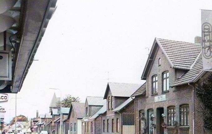 Nørregade.
Et farvet billede fra Fotograf Dall Schmidt nr. 74 og ned til Fr. d. 7's Gade nr. 1, hvor der ligger August Schlossers Smedeforretning.
Huset til venstre for Dall Schmidt er Vejen maskinfabrik. Huset blev opført i 1912.
A/S Vejen Maskinfabrik v. F. Olesen.
I 1957 var det Ingeniør Kalmar Olesen, hvor huset kom til at hedde Vejma Vejen Maskinfabrik.
Der var på det tidspunkt ikke så meget trafik som i dag. I 1950erne var Vejen en rolig by.
Til venstre kan man lige skimte reklameskiltet af Texaco Trafik Center Nørregade 73-75. 1980.
Allan Harboe
øj øj øj, hvor har vi mange gange stået og betragtet portrætbilleder, der var udstillet i vinduet - leder så tankerne over på Kim Larsen og 