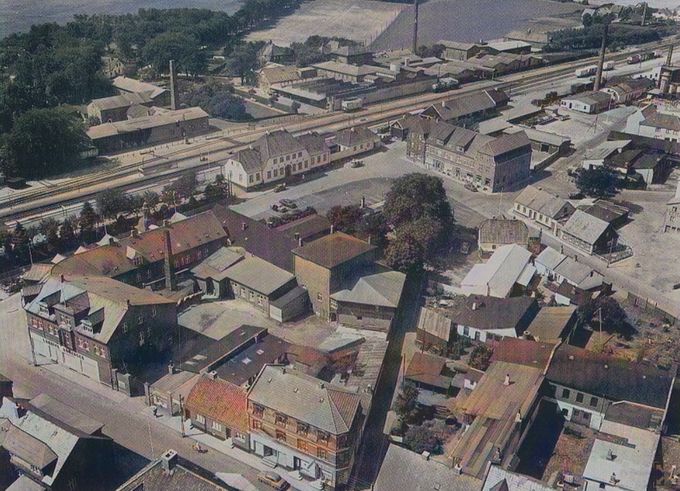 Cirka 1950.
Et Vue over Nørregade, Hansens Hotel, Banegårdspladsen,  Phønix og Cikorie fabrikken  Nørrejylland   med skorstenen og   Alfa på den anden side af Jernbanen.
Med lidt kulør på.
Nederst i billedet er det Nørregade 10, med min   Frisør Hans Henning Jørgensen,  og til højre for ham Gyden ind til Banegårdspladsen. 
Oppe i højre side er det indgangen til Phønix tagpap fabrikken. Og til højre for Brugsforeningen er det Vejens første Rutebilstation  hvor vejen ned til højre side er Jernbanegade.
De tre skorstene på den anden side af jernbaneskinnerne er til venstre Cikorie fabrikkens. Fabrikken blev revet ned omkring 1970, så er det Alfas, den største skorsten i Vejen den gang, som fløjtede til Middag og Aften. Dengang kørte man på cykel eller man gik hjem, til middag, også skoleeleverne. Hele landet indførte lørdagsfri i folkeskolen og gymnasiet den 1. august 1970. Og helt oppe i højre hjørne er det Dampkedel fabrikken  Mjølner, der lukkede i 1916. 
Oppe i venstre hjørne kan man lige skimte Vangen og kastanjealleen op til Grønvang gården, med alle Grønvangs marker ved Vesteralle. Ved direktør 0. Vang-Lauridsens død i 1957  blev Vangen opkøbt til Handelsskolen  i 1959. Jeg hører at Handelsskolen Jyllandsgade 11, skal sælges nu og skal flytte op til Petermindesvej. Gad vide hvad der så skal være i Handelsskolen.
