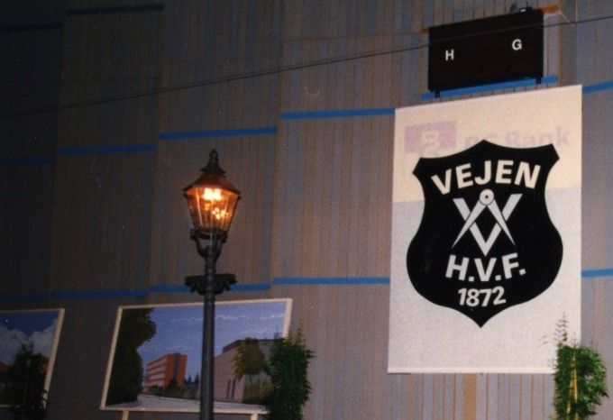 Vejen Håndværkerforening Fra 125 års jubilæet i 1997. Udstilling af J. D. Flansmoses malerier i Vejen hallen.
Jens Flansmose har lavet mange malerier fra Vejen. Her til højre er det Gæstgivergården som hvidmalet.
Og til venstre den ny Phønix tagpapfabrik bygning ved Banegårdspladsen.
Vibeke Degn Linnet Johannessen
De 2 fine lamper kommer fra Velamp A/S, som er et selskab under Uldalls Jernstøberi A/S. Lamperne m.m støbes også i dag.
Arne Beck
Jeg tror at de to lygter kommer fra Uldall´s jernstøberi ude i Søndergade. Jeg var nemlig med til at arrangere en Phønix fest engang hvor vi var ude på støberiet og låne nogle støbejerns lamper magen til dem på billedet.