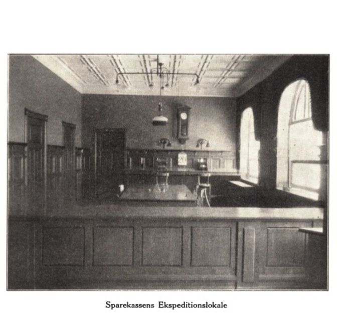 EJNER THYGESEN.
Det kostede 18860,19 kr. at opføre sparekassens nye bygning og et billede som der så ud i lokalet i 1909.
Eva Hedegaard.
Jeg husker kassen, hvor man kom med sin sparegris, fik den tømt og sat pengene ind på sin konto. Imellem kassemedarbejderen og kunden var et metalgitter, hvor der var fastgjorte de gule kronemønter: to kroner (en daler), enkroner og en enkelt halvkrone.