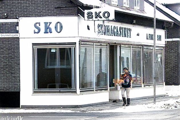 Et flot billede af Skomagasinet.
Yvonne Fink skriver.
Hej Johs. Mange tak for det fine billede, det er sjovt at se. Min mand og hans far købte butikken I 1964, men dengang var der renseri og 3 lejligheder. I starten var skobutikken kun halv så stor da der også var en lejlighed ud til Nørregade. Butikken blev udvidet af flere omgange. I 1991 flyttede vi butikken et hjørne længere op mod byen ( Nørregade 50)  og i 1995 blev der lavet 4 lejligheder på Nørregade 70/ Grunnetsgade, da vi ikke kunne sælge butikken.
   Nørregade 50 Autoværksted J. Kjær Jørgensen hvor vi flyttede hen. Vi købte af Klockmann Sko, som købte det i 1975 og da vi flyttede fik butikken nyt navn fordi folk altid spurgte i telefonen om det var hos Fink, når vi sagde Skomagasinet.