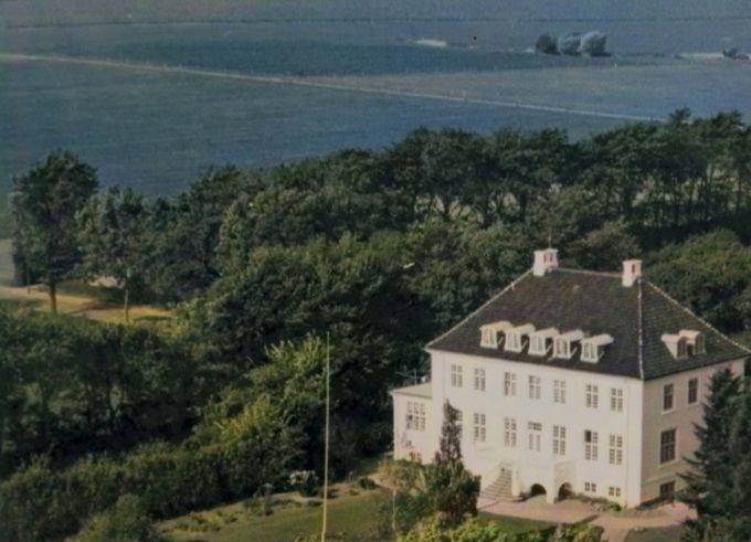 Brejdablik, Askovvej 31. Luftfotografi, set fra havesiden. Opført som privatbolig for Købmand P. Lauridsen, 1912.  Senere Børnehjemmet Brejdablik.
Ja også Brejdabliks have var lige så smuk som huset.
Det er utroligt hvor mange træer der var der i 1940 og 50erne. Om det er en landskabsarkitekt der har plantet træer og buske ved jeg ikke. Ej heller om de fandtes den gang. Jeg har altid synes at udbygningen af Brejdablik skæmmede huset. Men ved også at det var nødvendigt med den.
Nederst i billedet er det Holger Engelbrekt Pedersens mark. Hvor køerne gik helt op til tjørne hækken. Flagstangen nede til højre var  Bakkehusets have nummer 29.
Jeg kiggede altid på det slanke træ til højre for Brejdabliks flagstang, som jeg synes var et meget flot træ.
Til venstre i billedet kan man se lidt af Askovvej. Jeg spekulere på om det var før Askovvej blev asfalteret.
I dag er der et lyskryds der. Og fra venstre til højre var der træer på tværs af billedet ind  til Gården Grønvang. Og en lille sti videre ned til Vestergade. I dag er det bebygget af boliglommen Grønvangen.
Oppe til venstre på Grønvangs mark går stien fra Grønvang til Petersminde gården. Den har vi gået af utallige gange.
Oppe helt til venstre på Askovvej kan man se to af de flotte egetræer der stod fra Gunnersvej og op til Peterminde vejen.