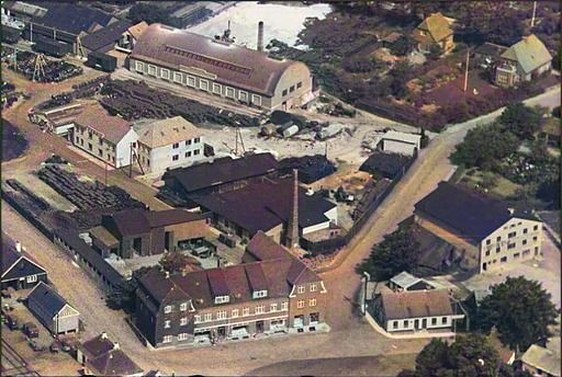 I 1880’erne og 90’erne havde Ebbe Sørensen Høllund på hjørnet af Askovvej og Søndergade, hvor Ford forretningen nu ligger
en Tagpapfabrik, og en Trælastforretning som lå ved Jernbanegade, tæt på Phønix.
...
Ebbe Sørensen Høllund. Han havde desuden tømmerhandel i Jernbanegade, som han solgte i 1902, da Vejen Trælasthandel blev oprettet.
Her ligger kornsiloen bag den første rutebilstation der var grønmalet.
Og den gamle flotte Brugsforening som lå på Banegårdspladsen, til venstre for Vejens første rutebilstationen. Lige ved indgangen til Phønix Tagpapfabrik bagved. Ved Phønix indgangen er der en skorsten der tilhørte Vejen Savværk.
Vejen Miniby skriver.
Fabrikation af Tagpap og Cementvarer.

Til Byggeindustrien hører ogsaa Fabrikation af Tagpap og Cementvarer.
I 80'erne og 90’erne virkede Ebbe Sørensen Høllund -
- hvis Navn man tit træffer paa, bl. a. i Sogneprotokollerne.
Han kom til Vejen 1877, var egentlig Bygmester -
- men ogsaa en dygtig Forretningsmand.
Det var ham, der købte Materialerne fra den gamle Kirke -
- men det var næppe store Ting han tjente ved den Lejlighed.
Paa Hjørnet af Askovvej og Søndergade, hvor Ford forretningen nu ligger -
- havde han en Tagpapfabrik -
- desuden en Trælastforretning som laa ved Jernbanegade.
Den sidste afhændede han i 1902 til A/S Vejen Trælasthandel -
- og købte derefter en Herregaard i Horsensegnen.
Oppe til højre er det Læge Frederik Hansen, skovvej 12-14 hus og Klinik. Skøde 20. december 1946 til Frederik Hansen. Lidt sjovt det var det år jeg blev født. Der var ikke så meget wellness dengang i starten af 1950erne, hverken ved lægerne eller tandlægerne.
Susanne Johannsen.
Der står noget om 