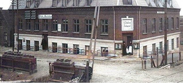 Nørregade 2. Højskolehjemmet.    I 1916 blev Højskolehjemmet nedrevet for at give plads til anlæggelsen af Troldhedebanen.
Ledvogterhuset der   ligesom Højskolehjemmet blev nedrevet  da Viadukten blev bygget i 1916. Ledvogterhus nr. 7.
 Urmager J. Schmidts forretning lå helt til  venstre  i Bygningen.
Den første bestyrer af Vejen Telefoncentral i 1886 var Urmager Iver Jørgensen Schmidt.
I 1931 overtog datteren Astrid Schmidt stillingen
Nedlagt i 1966.
Iver blev gift med Karen Marie Hansen den 26 Nov. 1886 i Ødis, Nørre Tyrstrup, Vejle, Danmark.27293 (Karen Marie Hansen blev født den 26 Mar. 1866 i Ødis, Nørre Tyrstrup, Vejle, Danmark, dåb i *, døde den 28 Apr. 1931 i Vejen, Malt, Ribe, Danmark og blev begravet den 3 Maj 1931 i Vejen, Malt, Ribe, Danmark 27295.)
Laurids Poulsen, f. 1865. Fotograf i Vejen fra 1893- ca. til 1918.
  Gift ca. 1894 med Andrea Gram.  (Fotograferne Gram & Poulsen). Rejste fra begyndelsen af 1890erne omkring og fotograferede gårde m.v.
Ved folketællingen 1901 kaldte han sig fotograf og afholdsvært (Vejen Højskolehjem).
Senere flyttede de til Gramhus, som blev til Vejen første Bibliotek  i Søndergade. Biblioteket Gramhus blev oprettet i 1916 i Søndergade nr. 2.
 ,,,,,,,,,
Man kan lige se nede i højre hjørne jernbane skinnerne.
Der står.
Der kørte ikke ret mange tog dengang, så opgaven var overkommelig. Men rækværket eller bommen skulle være på plads hver gang   dag og nat og i alt vejr. Derefter skulle ledvogteren træde frem og give signal til lokomotivføreren om, at alt var i orden.
Her kan man rigtig se bommen der skulle ned når der passerede et tog.
Nederst til venstre ude af billedet lå Ledvogterhuset.