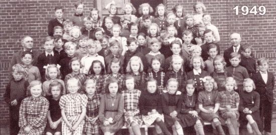 67 elever (37 piger og 30 drenge) fra 4. klasse fotograferet i 1949
- med lærer A. G. Johnsen tv. og overlærer Marius Mortensen til højre.
Fra Byskolen.