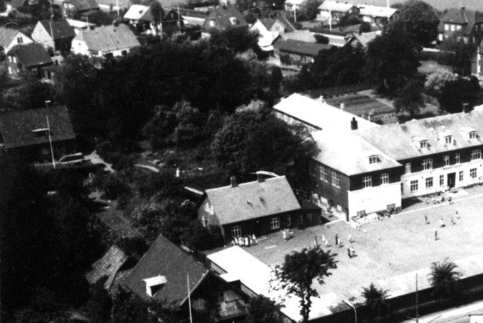  Luftfoto af Bakkely Skole og Søndergade, før udbygning i 1970 erne.
,,,,,,,,,,,
Et nyt billede af Bakkely skole.
Det er Søndergade på tværs nede i billedet.
Til højre nederst er det Grønnegade der går ud til højre, hvor der til højre i billedet ligger på hver side af Grønnegade til venstre Mælkebutikken. Mælkehandlerne var Christian Ø. Jensen 1959, og derefter Mortensen der boede på Gunnersvej. Og til højre Astrid og William Schmidt og
Gerda og Preben Schmidt`s Købmandshandel. Der startede med Tove og Volmer Jensen, der fik en dyrehandel i Søndergade til sidst. Butikken for dyrevenner, Søndergade 18.
Det hvide hus, med de to skorstene boede Harry Persson Pedel ved Bakkely Skole. Også som Sognefoged Harry Persson. Inden da arbejdede han ved Willadsens møbelfabrik. Hans søn Morten inviterede mig og flere andre ind for at se Robin Hood. Det var allerførste gang jeg så fjernsyn, og i sort hvid.
Sønnerne hed Torben og Mogens Persson.
Persson boede i Søndergade i det lange hvide hus, med de to skorstene, inden de flyttede til det idylliske hus på Torps Alle.
I dag er Hanne Persson med i denne gruppe.
Til venstre inde på skolepladsen var det Grethe og Inspektør Thor Rudkøbing Bakkely Skole som boede i det lille hus. Og da de flyttede op til Askovvej blev det brugt som klasseværelse. Det var Petersen fra Jensen og Petersens tøjforretning i Søndergade der byggede huset oppe på toppen af Askovvej, som Hr. og Fru Rudkøbing flyttede ind i. Jeg mener at Familien Pedersen boede i Østergade nr. 35. også.
Til venstre var det Willadsens privatbolig på hjørnet af Søndergade og Torpsalle.
Oppe til højre ved parkeringspladsen var det Skolelæge Heuch og hans kone Gerda der boede i huset i mange år, inden de flyttede til deres nybyggede hus på Askovvej. Læge Johan Christian Heuch 1891-1978 og Gerda Vilhelmine Kaae 1892-1982, der var Sygeplejerske.
Man kan lige se helt oppe til højre Askovvej og Allegade der går op i spidsen af billedet.
Oppe til venstre er det Gunnersvej.
Der var engang, men det er længe siden.
Hanne Persson.
Jeg kan lige tilføje at mine søstre Lizzy Olesen og Birte Christensen også er på Vejens venner. Mit barndomshjem Søndergade 45 var der to boliger vi boede i den ene og Ruth Melton Lie og hendes mand Asbjørn boede der da vi var børn.
Tonny Schwartz.
Christian Ø. var senere tagdækker på Phønix, hvor han tillidsmand for dem, han blev senere kasser på fagforeningen indtil han gik på pension. Han kom meget på Knudepunktet, han var en rar mand og han kunne huske utrolig mange personnumre og fortælle historier.