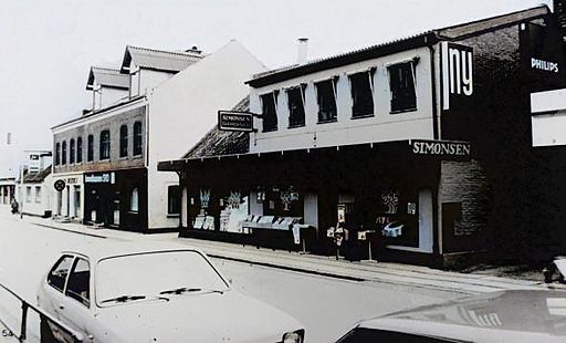 Simonsen Gardiner i Nørregade 29-31.
Helt til venstre er det Skovvejen ved Noras Tobak butik. Skovvej nr. 2.
Efter fru Holberg standsede, overtog Sønnen legetøjsbutikken og moderniserede den. Så det er efter at butikken lukkede at Simonsen Gardiner kom til.