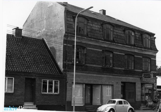 Bladcentralen som jeg husker den, op af de 5 trappetrin. Hvor det var Kioskejer Peder Pedersen der regerede.
Kioskejer Peder Pedersen som var beboer på adressen i 1957, og som havde været der i en menneskealder måtte springe for livet, da bulldoserne tog over. Man kunne ikke unde dem at blive til de gik på pension.
Og Damefrisør K. Bendtsen havde butikken til venstre for bladcentralen.