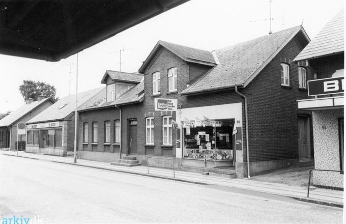 Husene Nørregade 85-89 i Vejen.
,,,,,,,,,,
Bladhandlen i nummer 89 i Nørregade, kan jeg ikke genkende.
Og der står heller ikke noget om den nogen steder.
Huset er opført i 1899.
Huset helt til højre som man kun kan se lidt af var nummer 91. Hørlücks Bageri og Skrædder Johannes Petersen. Og 2011 har Acacia Blomster butik i huset.
Til venstre er det Nørregade 85. som er opført i året 1900. Der var det Trikotagehandler Marie Schlosser omkring 1957 der havde butikken. Senere blev huset beboelseshus.
Jeg håber at det er rigtigt da jeg ikke genkender husene fra den tid.
Lis Munk Jensen.
I nr. 89 havde frøken Lorentzen sin lille butik hvor vi kunne købe fine former for tobak ..
Hun havde også flere andre varer . Når vi rigtig skulle drikke de fine sodavand fik vi lov til at købe en Valash.
Hun har en sød dame som levede og åndede for sin lille hund Doobie , som hun meget ofte havde under armen.
Frede Ulrich.
Nørregade 89 er jeg født. Min far ejede den og forpagtede den til frøken Lorentzen da vi flyttede til Malt i 1963.
Kirsten Hartvig.
Fru Lorentzen(Marta) lejede værelser ud til Johan Søndergård-kaldt Straus. Meget sød og venlig mand som mine forældre var ven med i mange år. Han har været ansat ved Falck.
Per Nielsen Svanemoos.
Jeg husker frk. Lorenzen som vi kaldte Sjulaima. Her kunne vi godt købe et par øl ved bagdøren lørdag aften. En herlig tid i -60 erne.