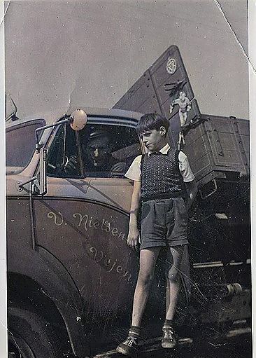 Niels-arne Hansen skriver.
En rigtig fin historie om Villy Nielsen. Er der en der har flere billeder af Villys biler. Så er jeg interesseret i dem.
Min Onkel Harry Rasmussen var hos Villy Nielsen i mange år. Han byggede med min tante Elly Rasmussen det sidste hus på Jættehøj ned til åen. 
Dengang var der ål i massevis også ørreder. Deres ven Bjørn Harbo var mange gange dernede og røge ål, og ørreder. Op i 1970erne var det slut med fisk i Vejen Å, så min tante måtte nøjes med de søer man skulle betale for at fiske.
Billedet her stammer fra Askovvej. Det var Phønix der asfalterede den for første gang, så min onkel var i fast rutefart til Kolding havn hvor jeg var med. Der var en tragt ved fabrikken hvor varm asfalt landede i ladet på lastbilen, og så hjem til Vejen igen. Jeg tror det var første gang i mit liv at jeg var på Kolding havn. Jeg kan ikke huske om jeg var begyndt i første klasse, eller var 6 år dengang.
Ja, lastbilen var gul og blå.