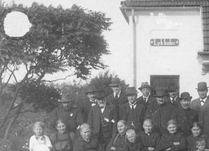 Der står.
 Huset Lykkebo i Vestergade.
   med ukendt persongruppe foran,  Lykkebo var nabo til Margarine fabrikken Alfa, der blev nedrevet i 1982.
Det er sjovt at i fotografiets barndom var personerne meget stive, og næsten ingen med smil. Man skulle koncentrere sig så meget at der ikke var plads eller overskud til at smile. Og så havde man selvfølgelig sit pæneste tøj på.
Der var i Vestergade to tvillingehuse, hvor det ene er der endnu. Det andet der hedder Lykkebo, så jeg blev nedbrudt af Entreprenør  Bjarne Nielsen, Villy Nielsens søn i 1982. Hvor tiden dog flyver afsted. I dag er der parkeringsplads på stedet.
Jeg kan ikke huske at det hed Lykkebo.
Det er altid trist at se et hus skal fjernes. Derfor er jeg ikke tilhænger af alle de nedbrydnings billeder man støder på.
I dag ligger der en parkeringsplads der.
Jens Aksel Kjær.
I 50'erne og 60'erne boede søskendeparret Metha og Jacob Søndergård i den del af huset som vises her.
Jacob havde tidligere opholdt sig i mange år i Argentina.
I den andre delen af huset boede familien Rudolf Nielsen som var fyrbøder på Alfa.
Jens Aksel Kjær  skriver.     Sigfred Larsens hus ses (det lille hvide) og hans kanin opdræt. Lidt af beboelseshuset til 