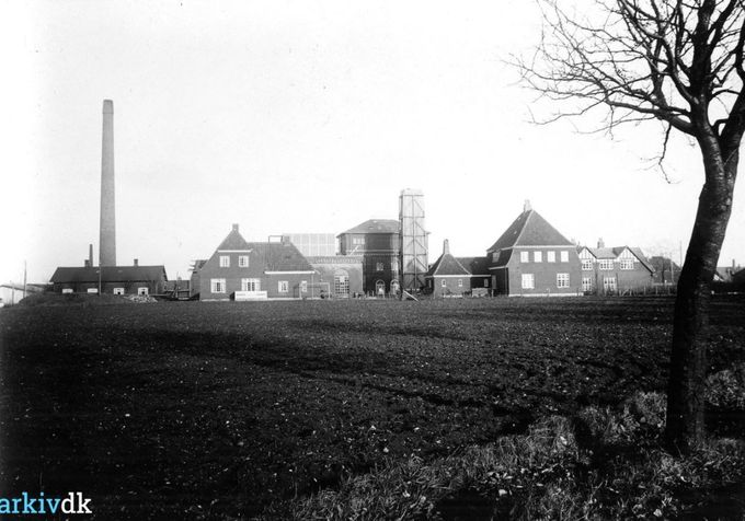 Margarinefabrikken Alfa, Vestergade, set fra Grønvangs Alle. Fra 1930'erne.
........................
Til venstre er det dengang Vejens største skorsten, der ved en troldefest fik Alfa navnet sat på skorstenen.
Til højre må det være starten på kastanje alleens træer der var en smuk alle` da jeg blev født i 1946. Jeg hentede i spandevis af kastanjer hjem, i 5-6 års alderen.
Huset til venstre ved skorstenen var til Alfas medarbejdere. Det har været et stort arbejde at få Margarinefabrikken bygget. Der blev bygget med mursten. Alfas fabriksbygning fra 1898 er tegnet af arkitekt Sophus Petersen.
Margarinefabrikken startede i 1898.
Flemming Kjær.
Min farfar boede i huset til venstre for skorstenen fra huset var færdig til 1943.
Jens Aksel Kjær
Tror faktisk at billedet det er meget ældre end 1930erne. Tror det er 25-30 år ældre.
Som Flemming Kjær skriver boede vores farfar i Vestergade 6 og jeg mener han flyttet ind der år 1900 eller ret efter. Farfar boede de første årene han var ansat på ALFA i Allegade og flyttet derefter til Vestergade.