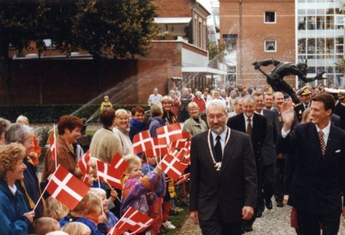 Prins Joakim og Borgmester Reinar Busk ses ved Vejen Museum Troldespringvandet ses direkte bag dem og folk og mange små børn står ved siden af gå-stien og vinker med flag. Prins Joakim vinker til folk Billede 1 af 3 i en billedserie.
Periode 1990 - 2000
Fotograf Photocare.
,,,,,,,,,,,,,
Det var i samme år 1995 han flyttede ind på slottet i Møgeltønder.
Jeg har fået et link .
https://jv.dk/artikel/underjordisk-samlingssted-skatere-f%C3%A5r-prins-joachims-gamle-bunker
Det viste jeg heller ikke.
At der har været en bunker ved Petersminde vej.